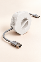 Enrouleur de câble portable Enroulo blanc avec câble tressé USB-A vers USB-C, sur fond crème
