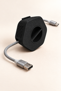 Enrouleur de câble portable Enroulo noir avec câble tressé USB-A vers USB-C, sur fond crème