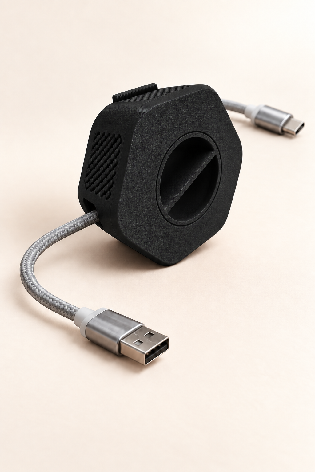 Enrouleur de câble portable Enroulo noir avec câble tressé USB-A vers USB-C, sur fond crème